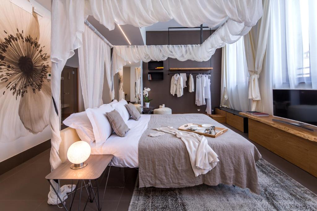 Mercatovecchio Luxury Suites في أوديني: غرفة نوم بسرير مظلة وتلفزيون