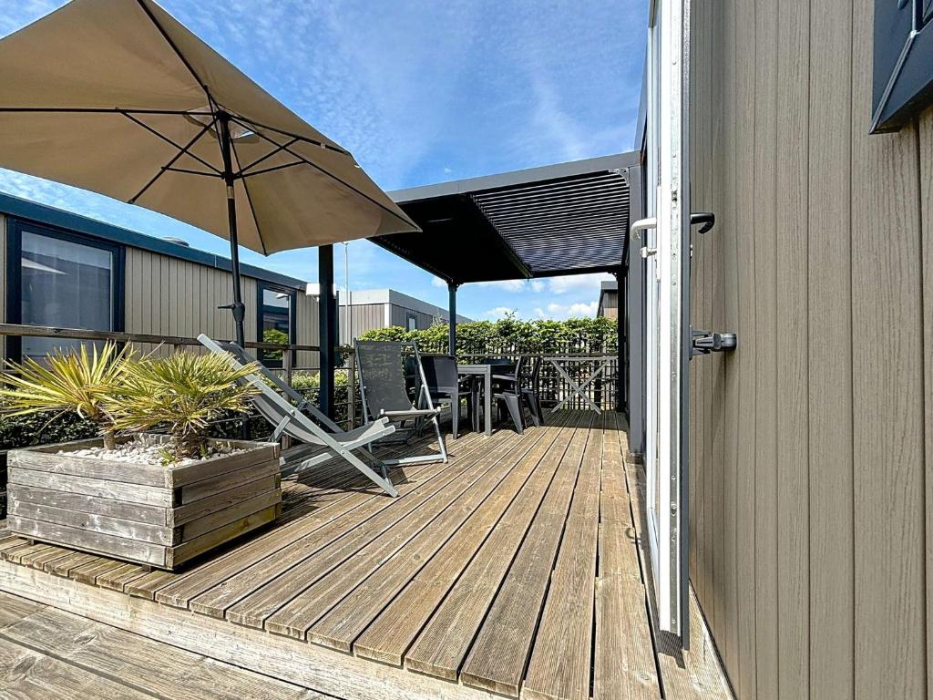 un patio avec un parasol, une table et des chaises dans l'établissement Mobil-home Grand Confort 4 pers, 2 chambres, 1 sdb, clim, terrasse & parking, à 200m de la plage - FR-1-361A-2, à Jullouville