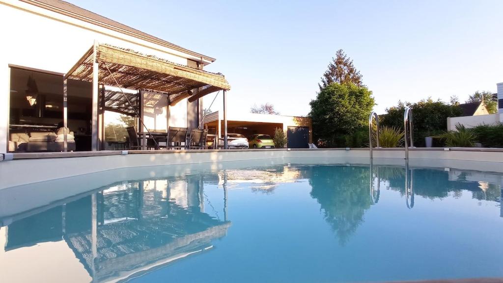 une piscine avec de l'eau bleue devant un immeuble dans l'établissement Villa 5km du circuit 24h Le Mans, à Spay