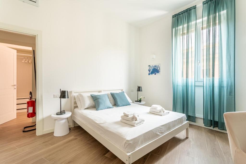 una camera bianca con un grande letto con cuscini blu di iFlat Stylish New Flat Steps from the Vatican a Roma