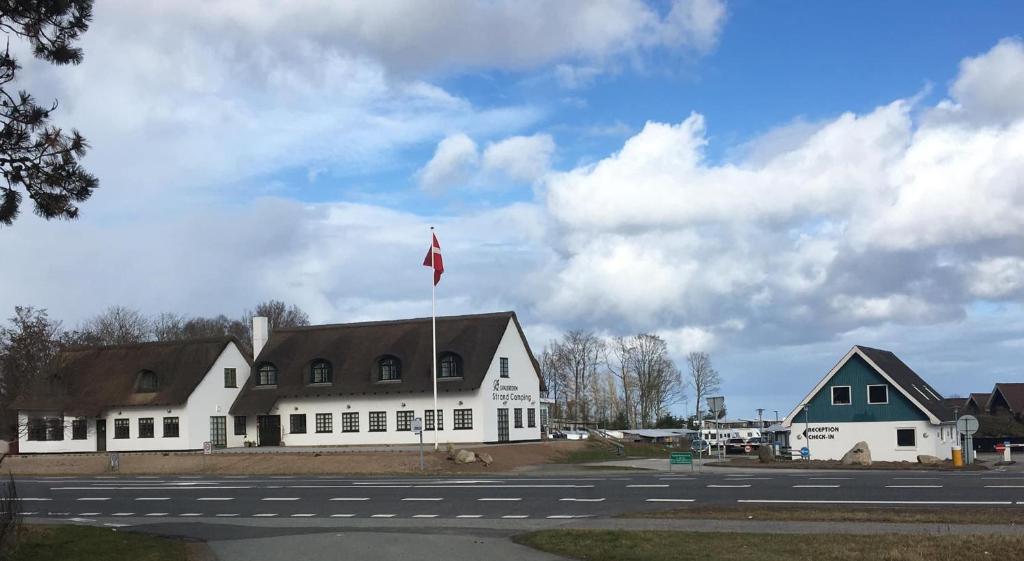 a white building with a flag on top of it at Svalereden Strand Camping Apartments in Frederikshavn