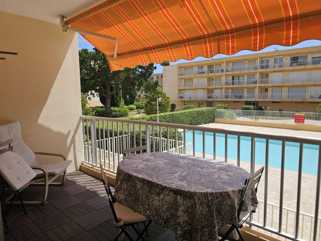 un patio avec une table et des chaises sur un balcon dans l'établissement Confortable 2 pièces au Lavandou avec balcon, clim et accès piscine - FR-1-308-120, au Lavandou