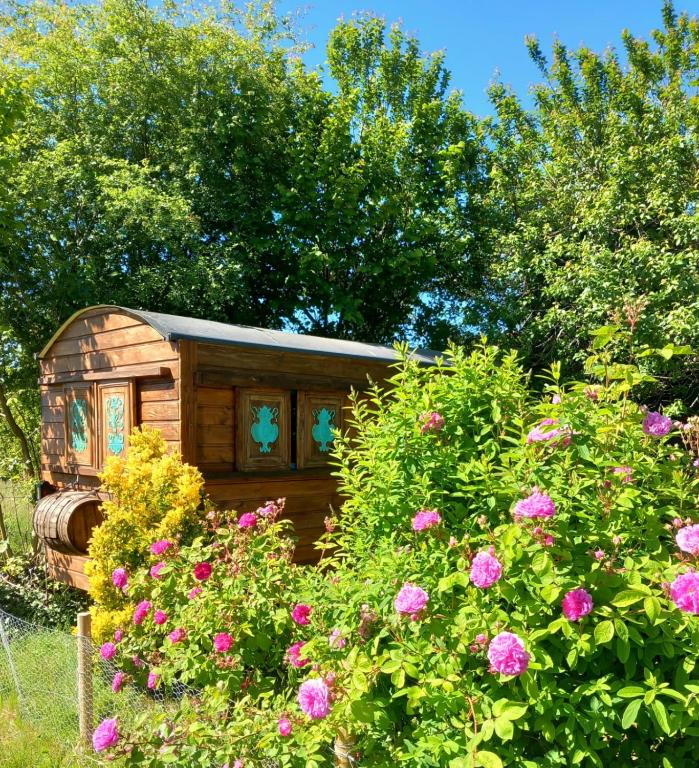 une petite maison en bois dans un jardin fleuri dans l'établissement Roulotte avec Spa, à La Capelle-Bleys