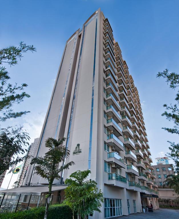 a tall white building with trees in front of it at Hotel Sequoia Alphaville in Barueri