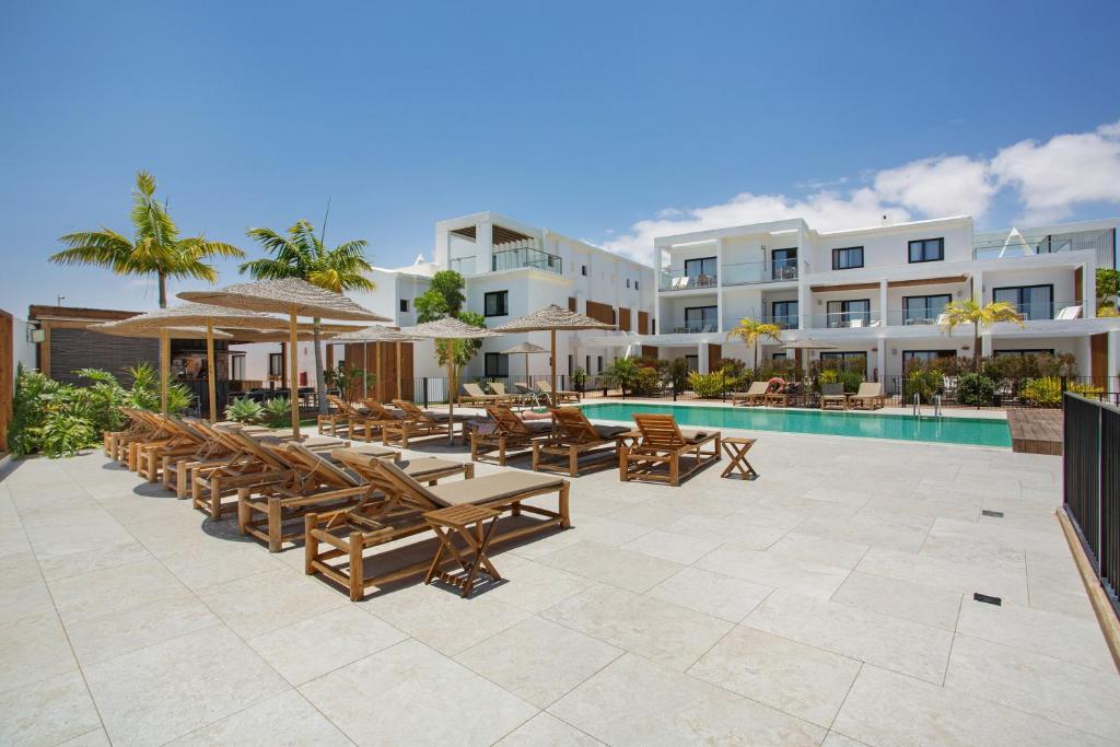 an outdoor patio with tables and chairs and a pool at Casa Sunrise in Parque Holandes