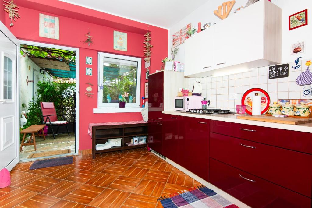 a kitchen with red walls and a wooden floor at Apartments Baredi in Izola