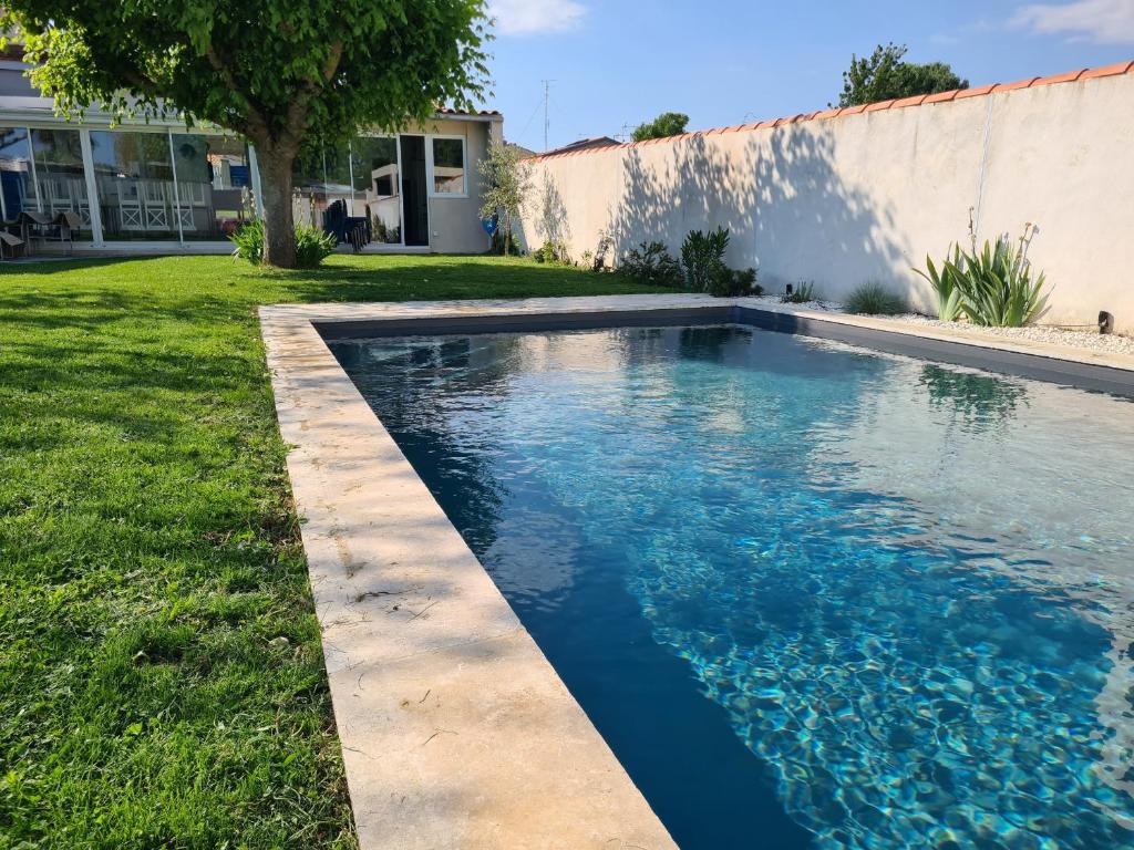 une piscine avec de l'eau bleue dans une cour dans l'établissement L'Olivière, à Fouras