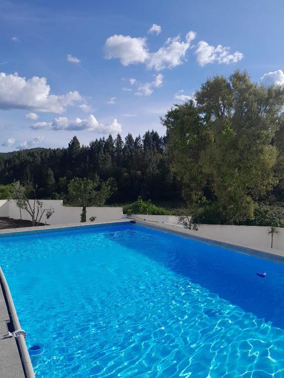 a large swimming pool with blue water at Casas da Vila in Vila de Rei