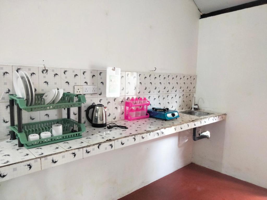 Una encimera de cocina con azulejos verdes y blancos. en Hotel jem, en Nikawatawana