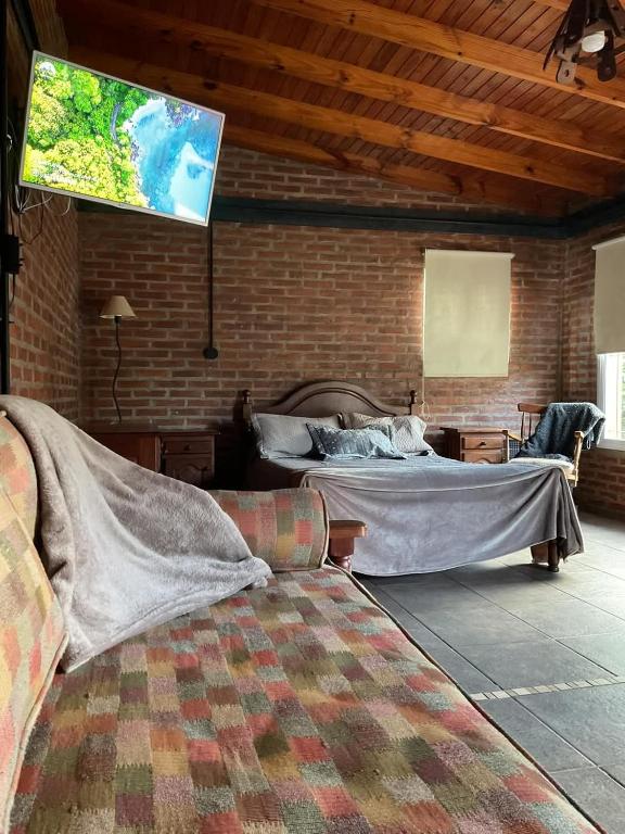 a room with two beds and a tv on a brick wall at Wisla Rellowed in Manuel B. Gonnet