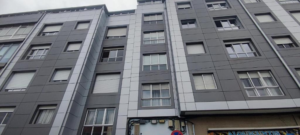 a tall gray building with many windows at Rosalia Rooms in A Estrada