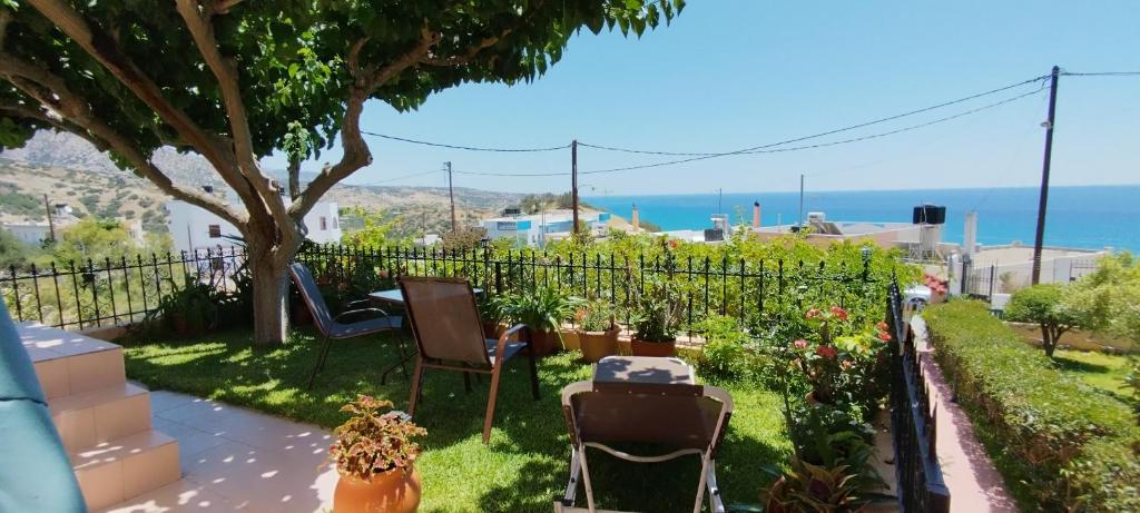 a garden with a table and chairs and the ocean at Despoina Apartments in Keratokampos