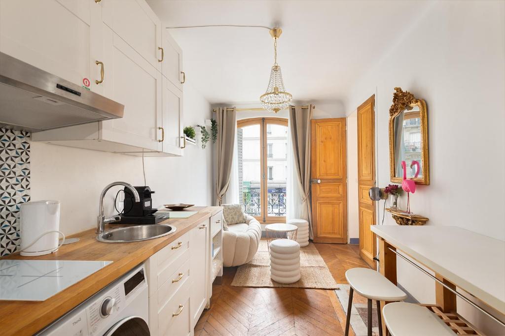 une cuisine avec des armoires blanches et un évier dans l'établissement Haussmannian elegance close to Montmartre, à Paris