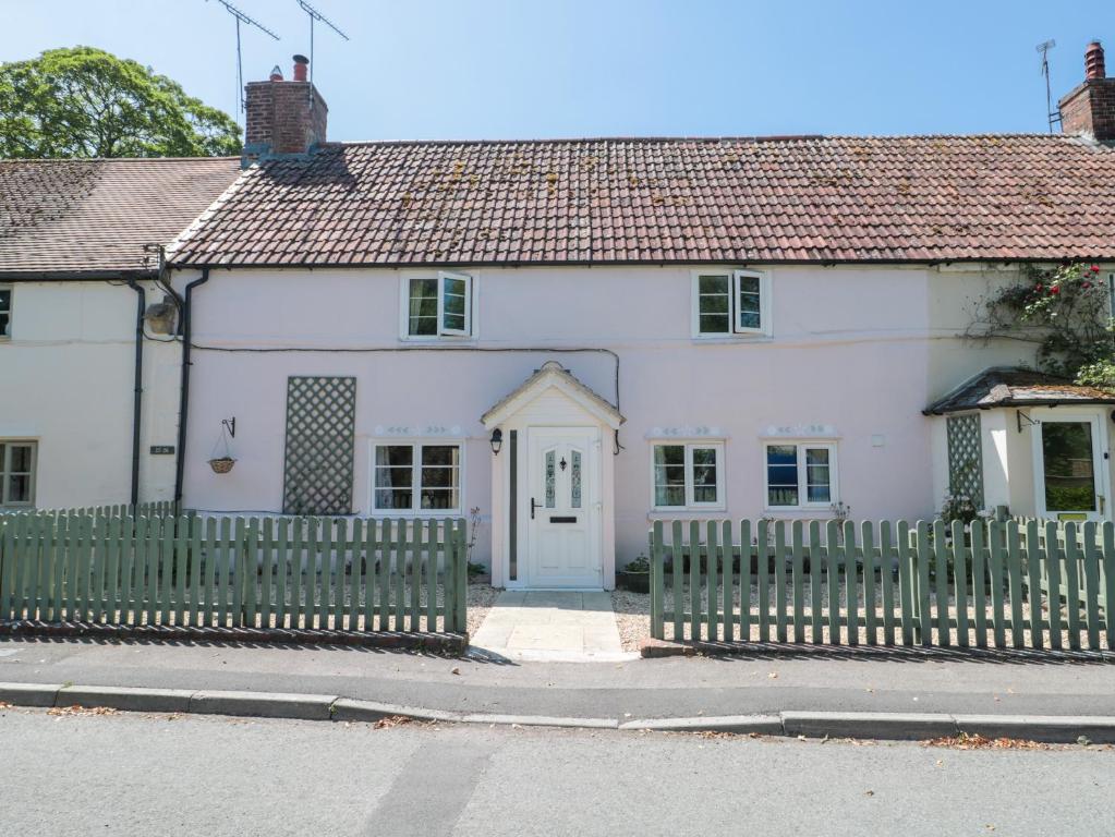 a white house with a fence in front of it at Old Farm Cottage in Warminster