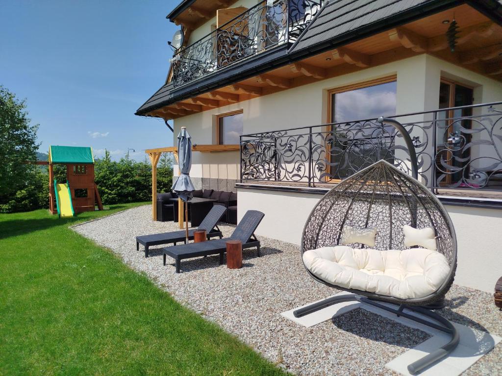 a patio with chairs and a swing in front of a house at Chata Koziniec przy wyciągu in Czarna Góra