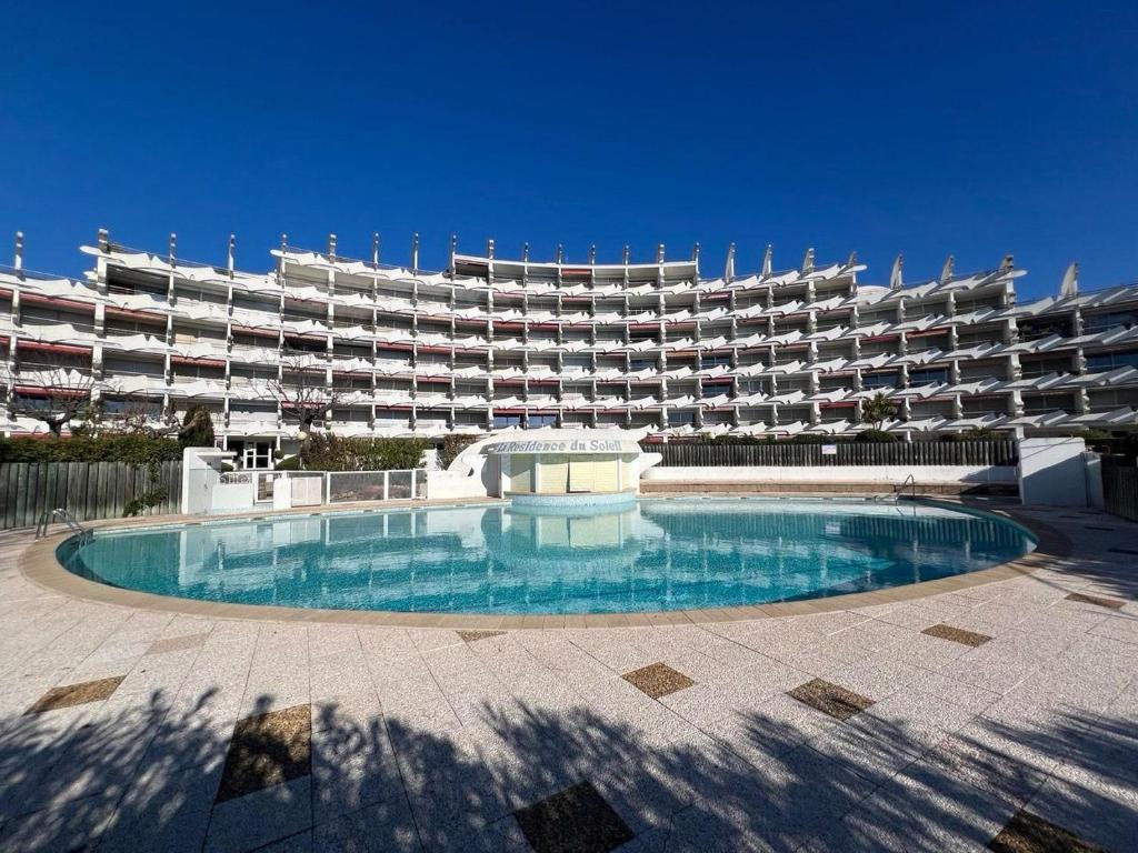 un grand bâtiment avec une piscine en face d'un bâtiment dans l'établissement Studio 4p, cozy, 100m mer , piscine, au pied des commerces, à La Grande Motte