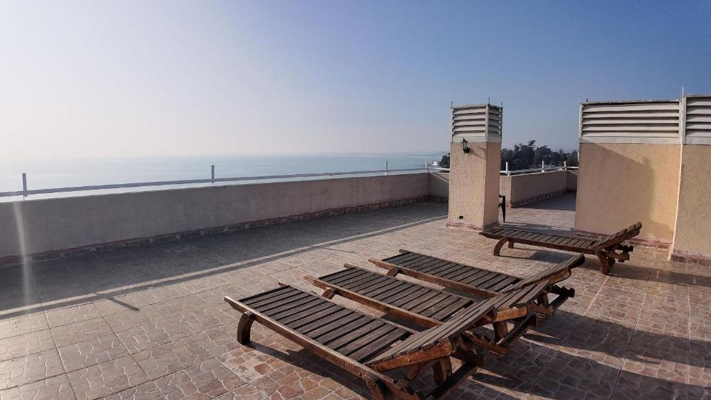 two benches sitting on top of a building near the ocean at Departamento Familiar en Concón in Concón