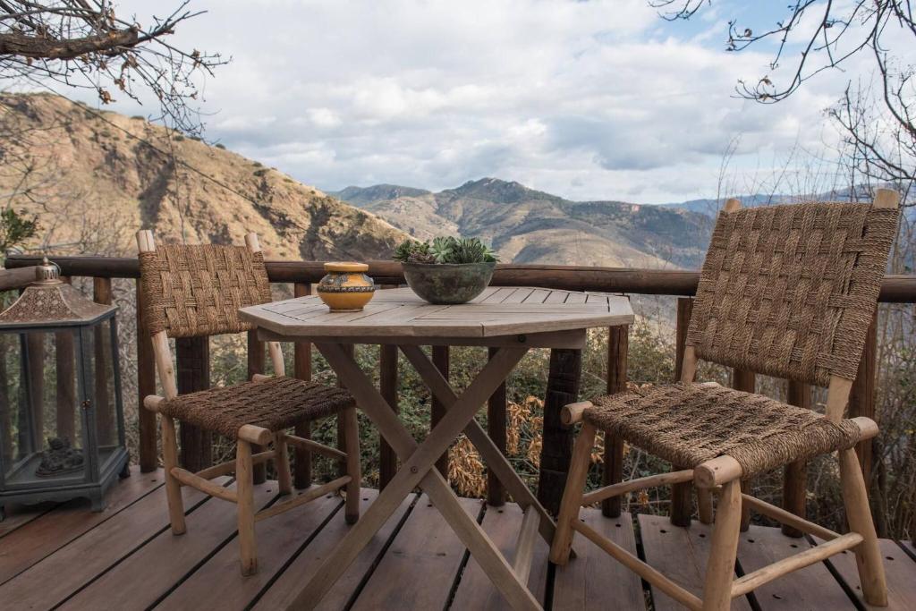 un tavolo di legno e due sedie su un ponte con le montagne di Casa WalhallaCorti jo Pramo a Pampaneira