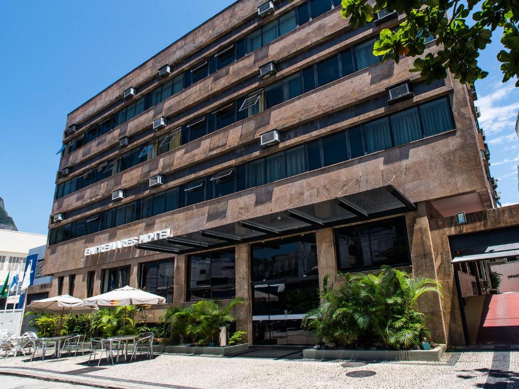 a building with tables and umbrellas in front of it at Entremares Hotel in Rio de Janeiro