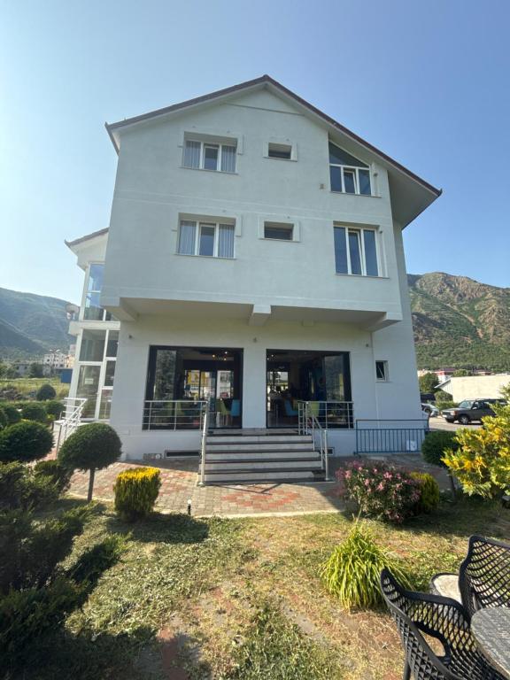 a large white house with some chairs in front of it at Bar-Hotel IRDI in Bulqizë