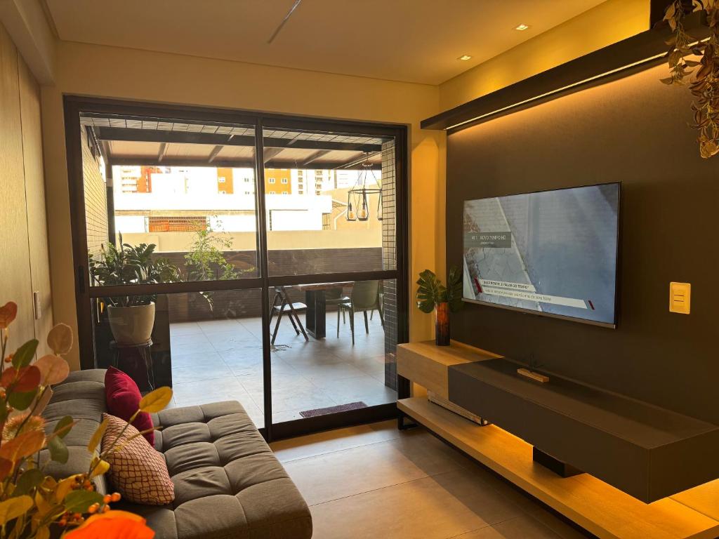 a living room with a couch and a flat screen tv at Lindo terraço perto do mar in João Pessoa