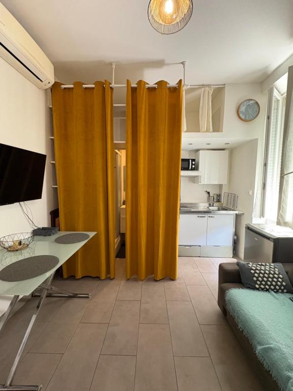 un salon avec des rideaux jaunes dans une cuisine dans l'établissement Charmant studio en centre-ville, à Ajaccio