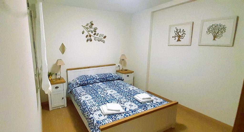 a small bedroom with a bed with blue and white sheets at EnFOZ Playa A Rapadoira in Foz