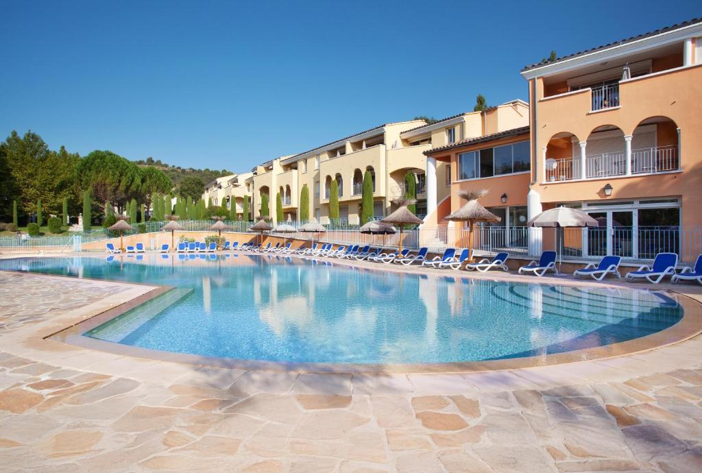 a large swimming pool with chairs and umbrellas at Résidence Odalys La Licorne de Haute Provence in Gréoux-les-Bains