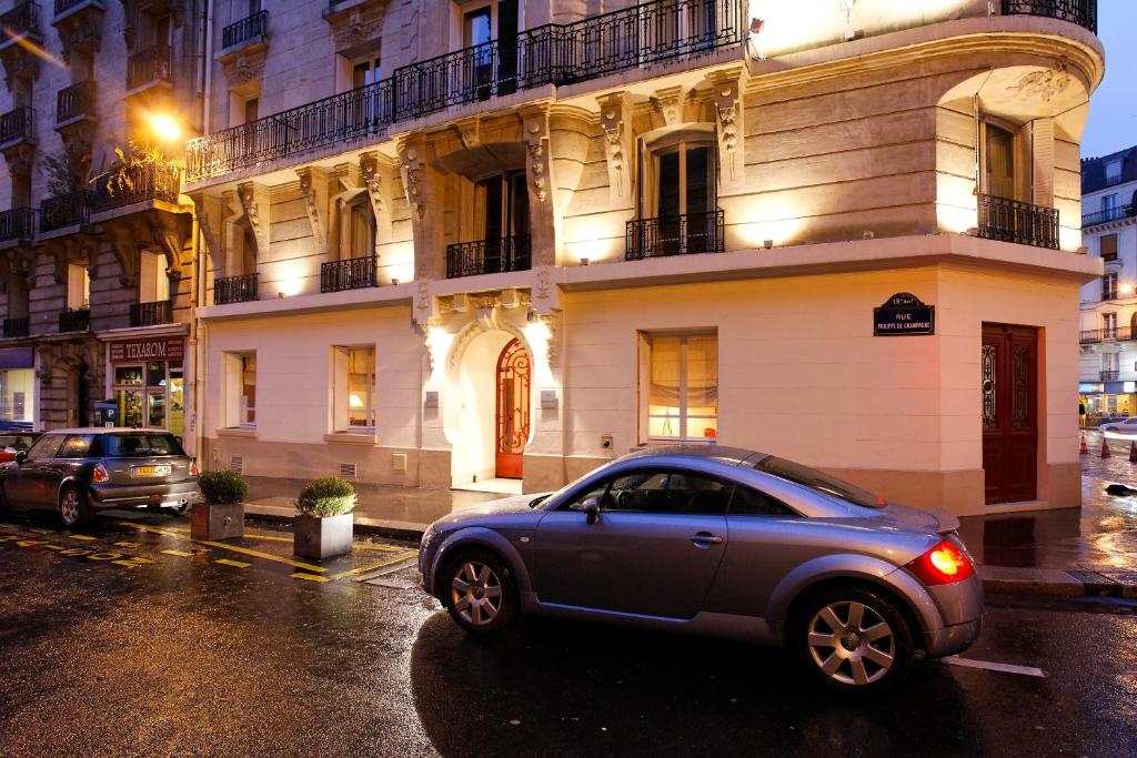 une voiture garée dans une rue en face d'un bâtiment dans l'établissement Hotel La Manufacture, à Paris