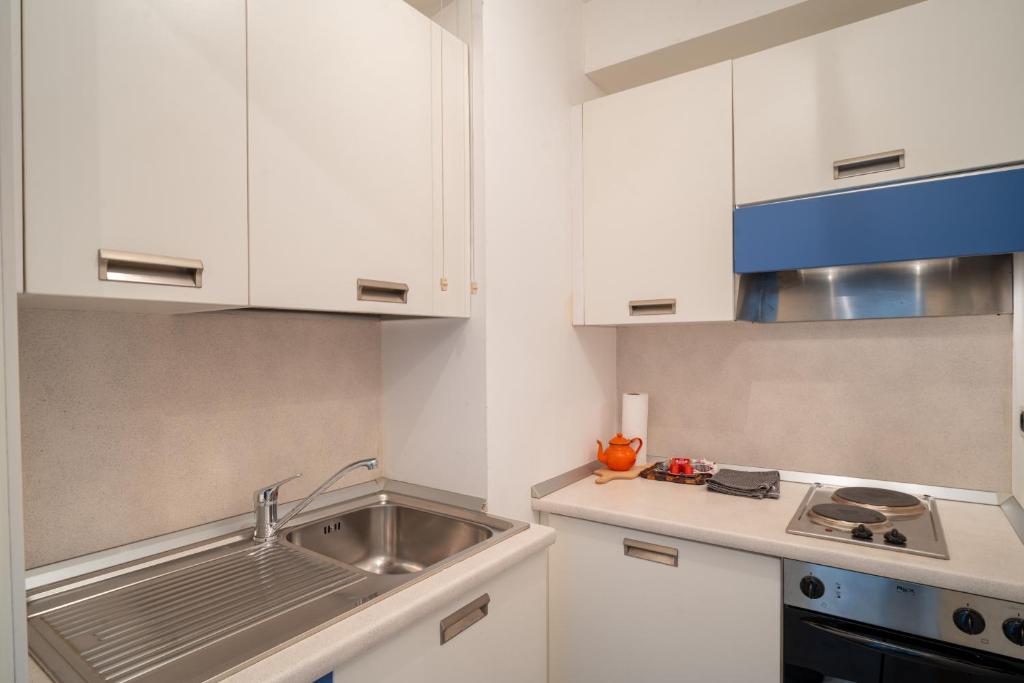 une cuisine avec des armoires blanches et un évier dans l'établissement Montecarlo vista - Sea view, à Beausoleil