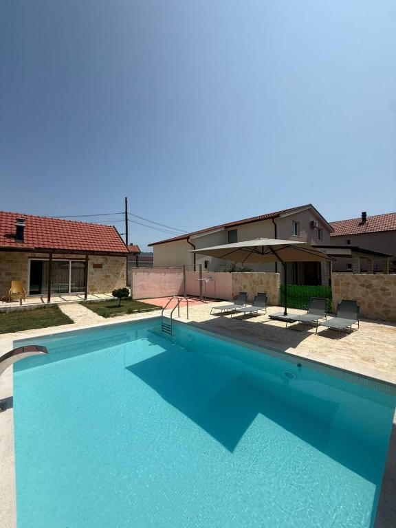 a large swimming pool with two chairs and a house at Mila in Danilovgrad