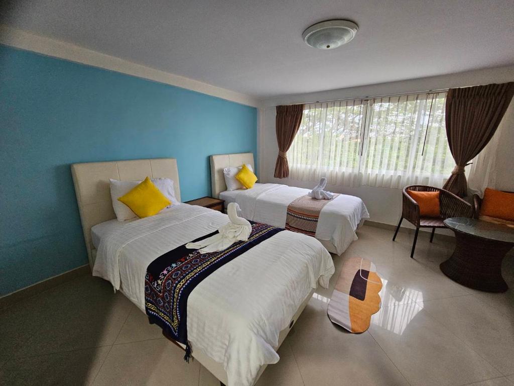 a hotel room with two beds and a window at Hello Jomtien in Jomtien Beach