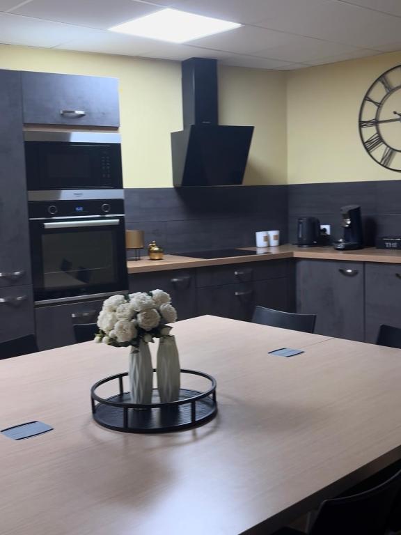 une cuisine avec une table avec un vase de fleurs dessus dans l'établissement Les Halles, à Chaumont