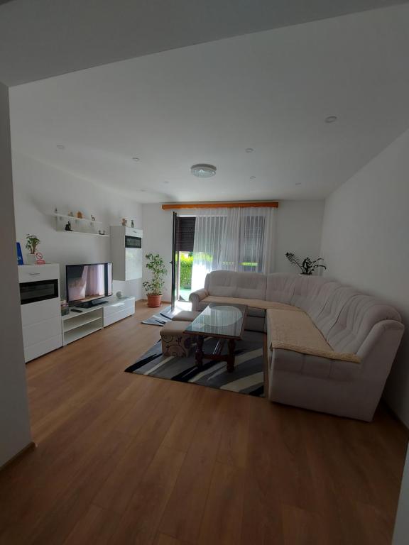 a large living room with a couch and a tv at Apartman Aldina in Bihać