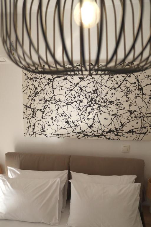 a chandelier hanging over a bed with white pillows at Cocoon Urban Suites in Kavála
