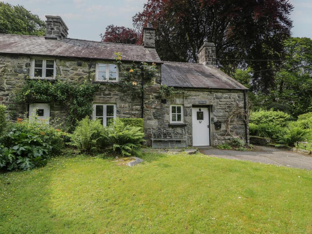 an old stone house with a white door at Glandwr Cottage in Llanbedr