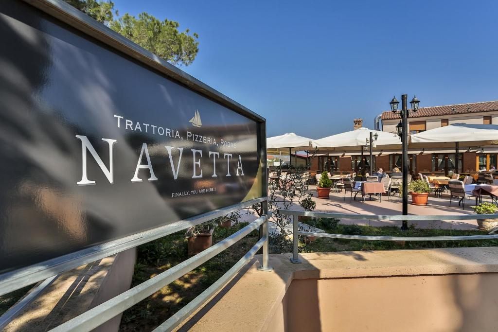 a sign for a restaurant with tables and chairs at Guest House Navetta in Fažana