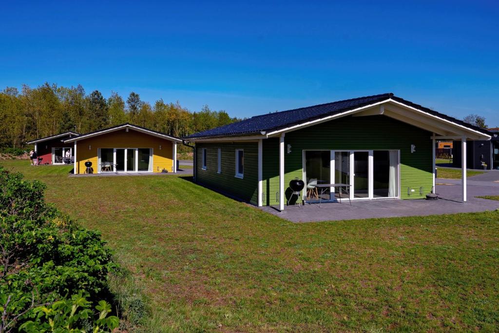 a green and yellow house with a large yard at SKAN-PARK Ferienhäuser & Tiny Houses am Bärwalder See in Jahmen Ausbau