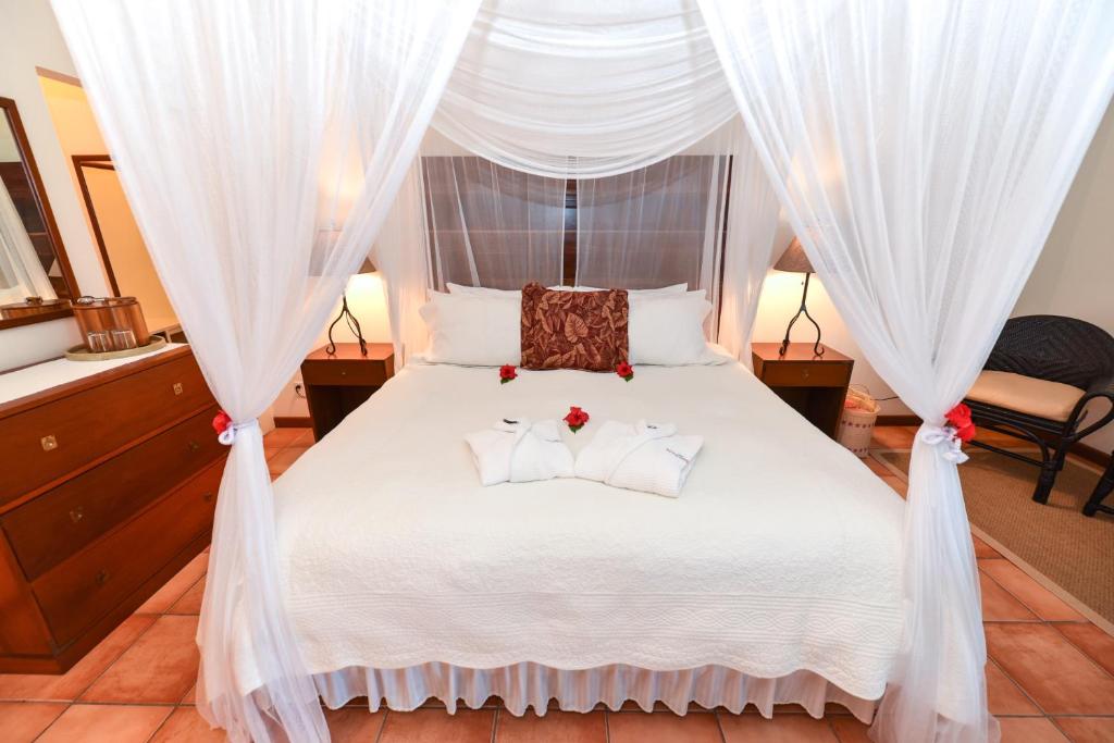 a bedroom with a white canopy bed with two pillows at Victoria House Resort & Spa in San Pedro