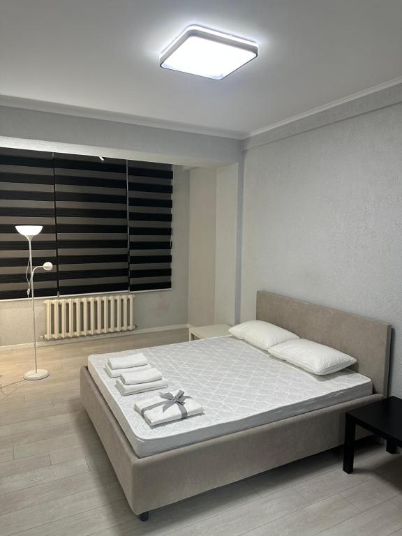 a bedroom with a bed and a lamp and a window at Frunze Apartment in Bishkek