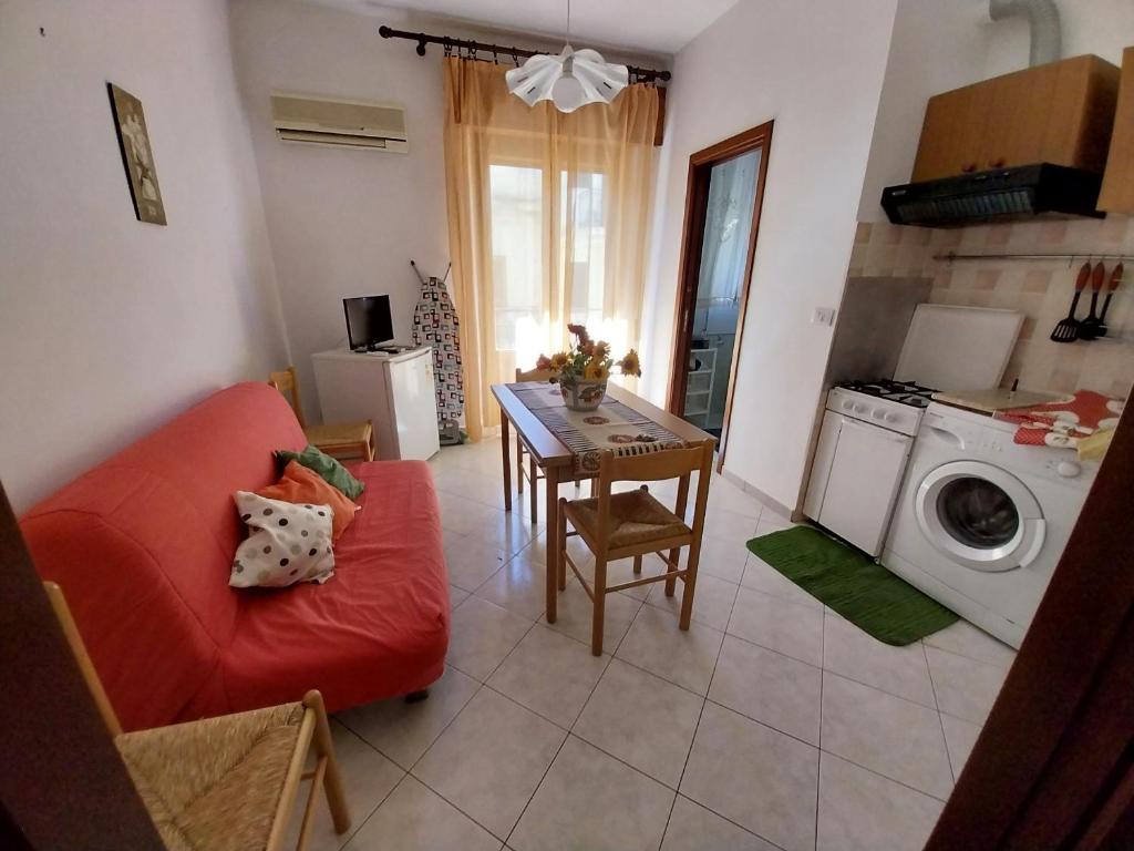 a living room with a red couch and a table at Caterina in Isola delle Femmine