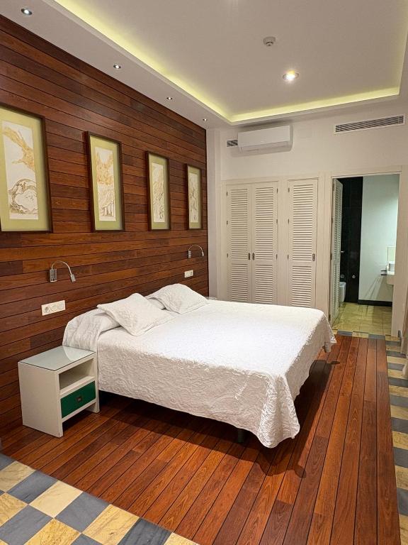 sypialnia z białym łóżkiem i drewnianymi ścianami w obiekcie Hostal El Alojado de Velarde w mieście Conil de la Frontera