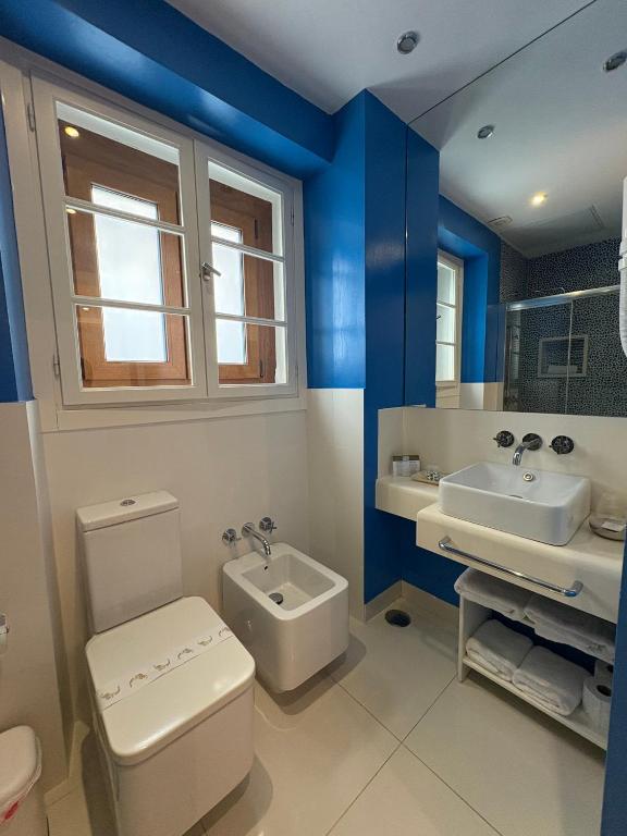 Łazienka z niebieskimi ścianami, toaletą i umywalką w obiekcie Hostal El Alojado de Velarde w mieście Conil de la Frontera