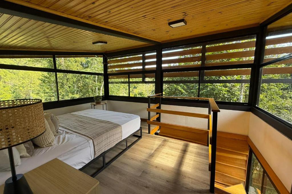 ein Schlafzimmer mit einem Bett in einem Zimmer mit Fenstern in der Unterkunft Casa Selva Negra in Talamanca