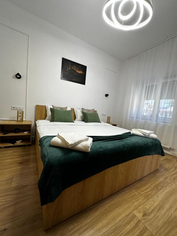 a bedroom with a large bed with a green blanket at Moin Apartment in Sibiu