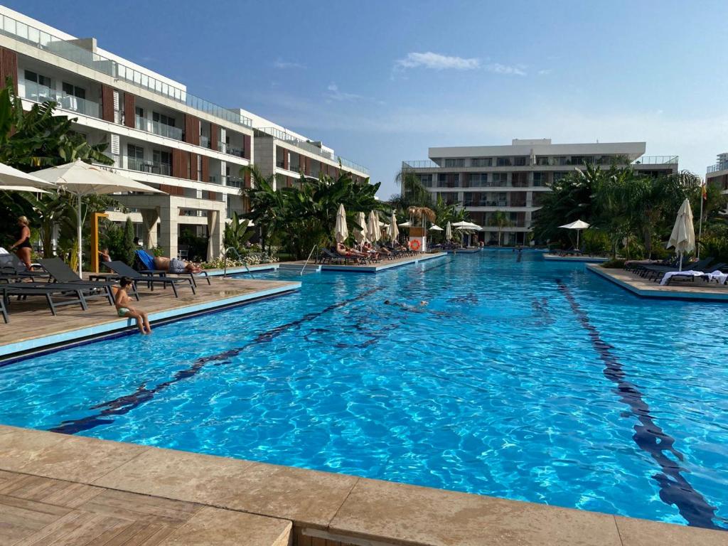 a large swimming pool with chairs and umbrellas in a hotel at Iskele Courtyard Long Beach Apartment in Iskele
