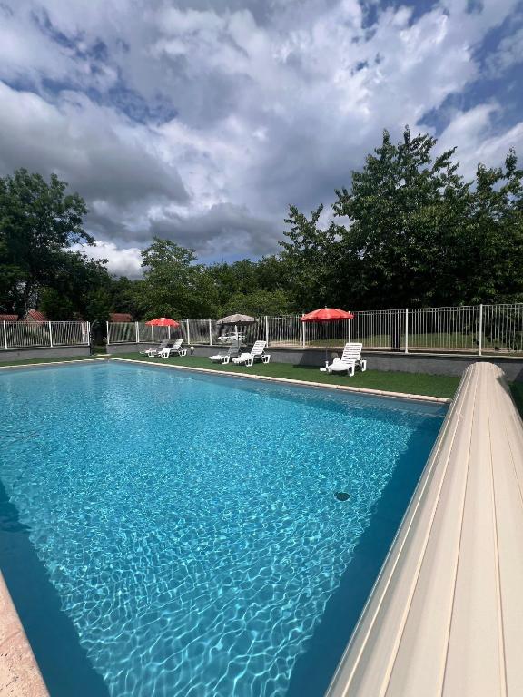 une grande piscine bleue avec chaises et parasols dans l'établissement Les Caselas, à Gramat