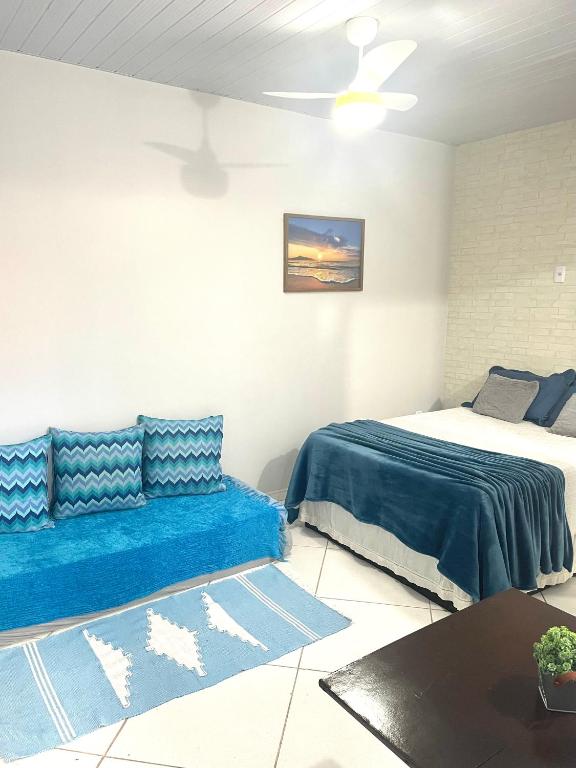 a bedroom with a bed and a blue couch at Kitnet aconchegante in Rio das Ostras
