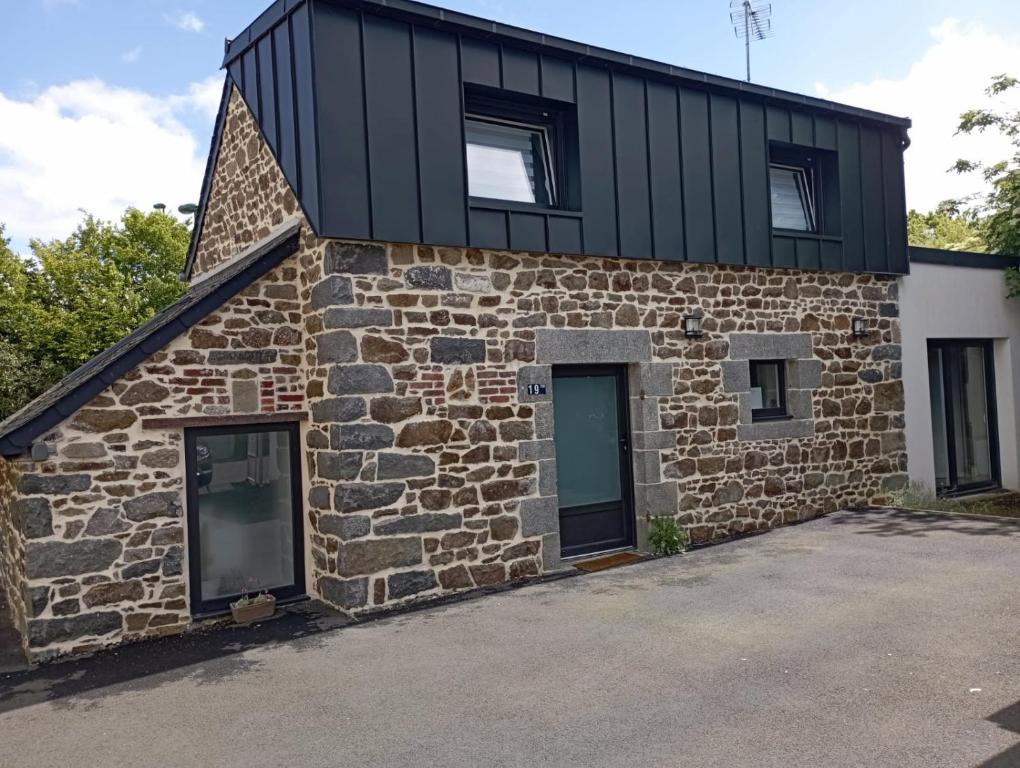 une maison en pierre avec un toit noir et des fenêtres dans l'établissement Petit nid douillet-Palais des congrès et des expositions St Brieuc, à Ploufragan