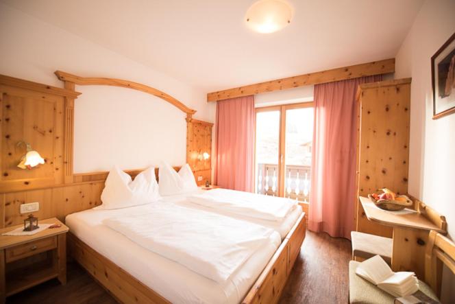 a bedroom with a large white bed with a window at Mahlknechthuette Seiseralm in Alpe di Siusi